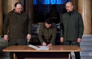 Presiden Ukraina Volodymyr Zelenskiy menandatangani permintaan resmi agar Ukraina bergabung dengan Uni Eropa, dengan Perdana Menteri Denys Shmygal (kanan) dan Ketua Parlemen Ruslan Stefanchuk berdiri di sampingnya, di Kiev, Ukraina, Senin (28/2/2022).  