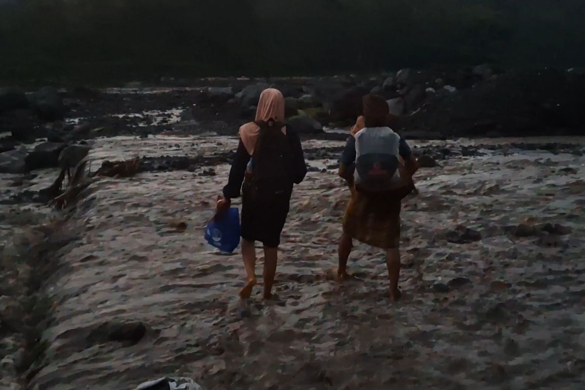 Sintia menyebrangi banjir lahar hujan Gunung Semeru digendong tetangganya, Jumat (17/1/2025)