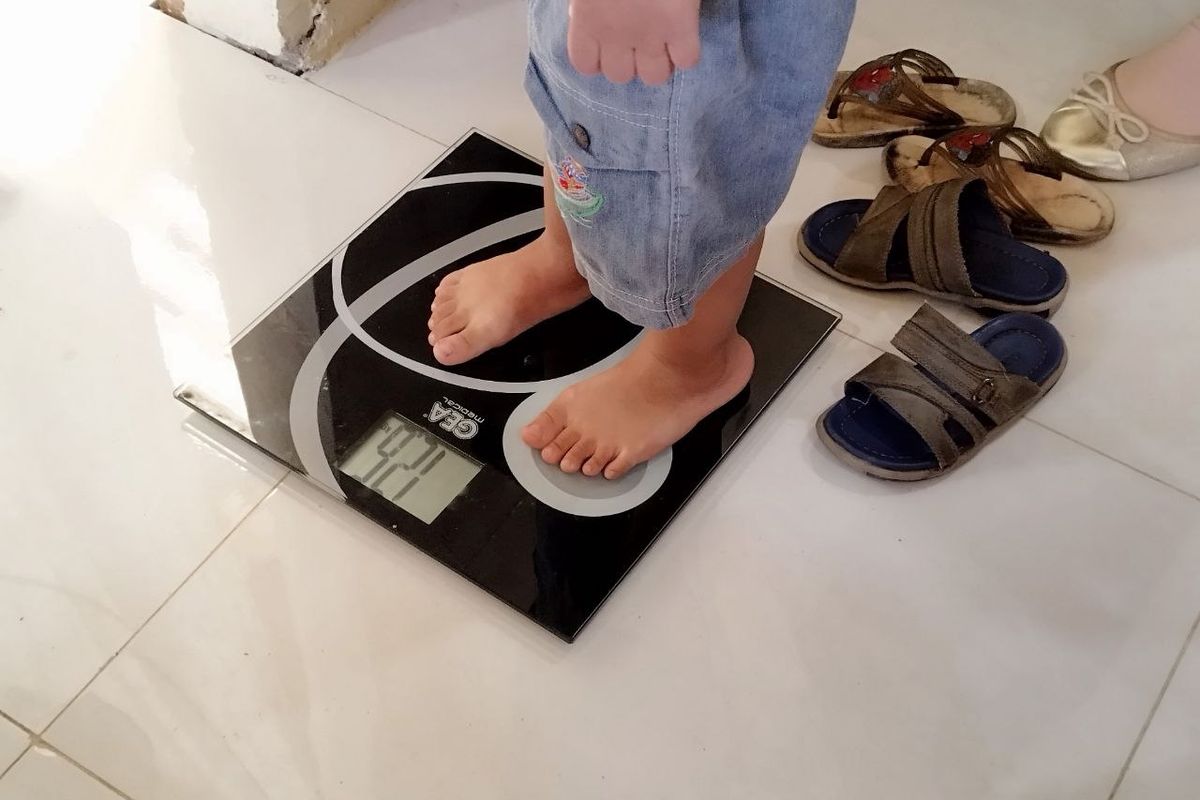 Seorang anak balita melakukan pengukuran berat badan di Posyandu RW 006 Cempaka Putih Barat, Jakarta Pusat, pada Senin (3/4/2023). (KOMPAS.com/XENA OLIVIA)