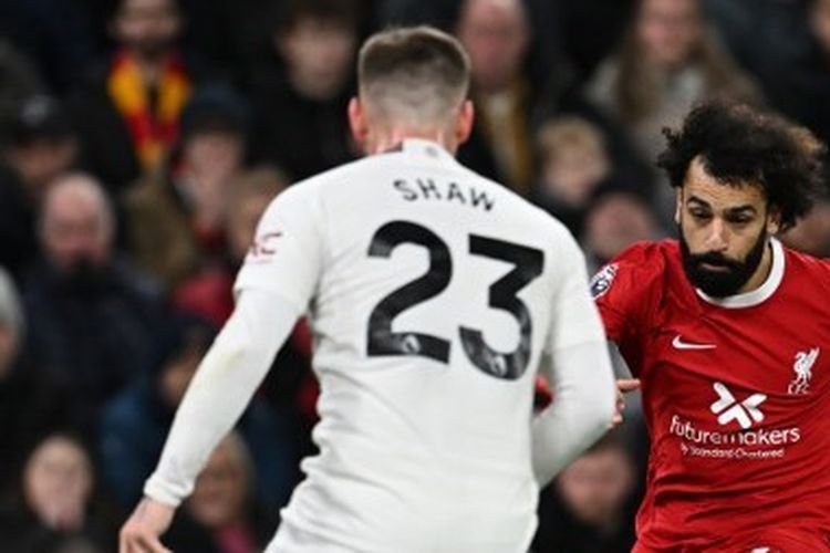 Pemain sayap Liverpool, Mohamed Salah (tengah), melepaskan umpan di antara penjagaan dua pemain Manchester United, Luke Shaw dan Alejandro Garnacho. Laga Liverpool vs Man United pada pekan ke-17 Liga Inggris 2023-2024 tersebut digelar di Stadion Anfield, Minggu (17/12/2023). (Foto oleh PAUL ELLIS/AFP)