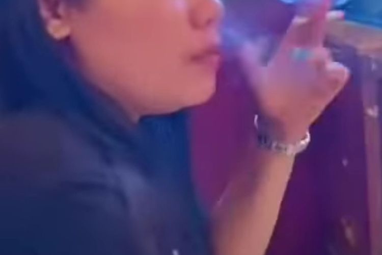 Tangkapan layar seorang perempuan sedang duduk sambil merokok diduga salah ruangan Polres Sikka
