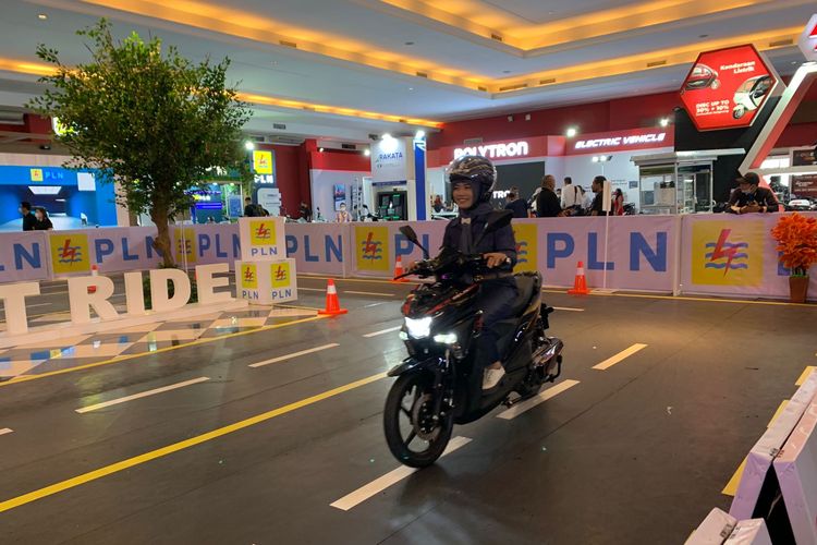 Ilustrasi seorang wanita mencoba motor listrik di arena test ride IIMS 2023