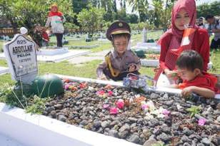 Arsana (5) sedang menaburkan bunga di Taman Makam Pahlawan Wisma Raga Satria Banyuwangi Rabu (31/8/2016)