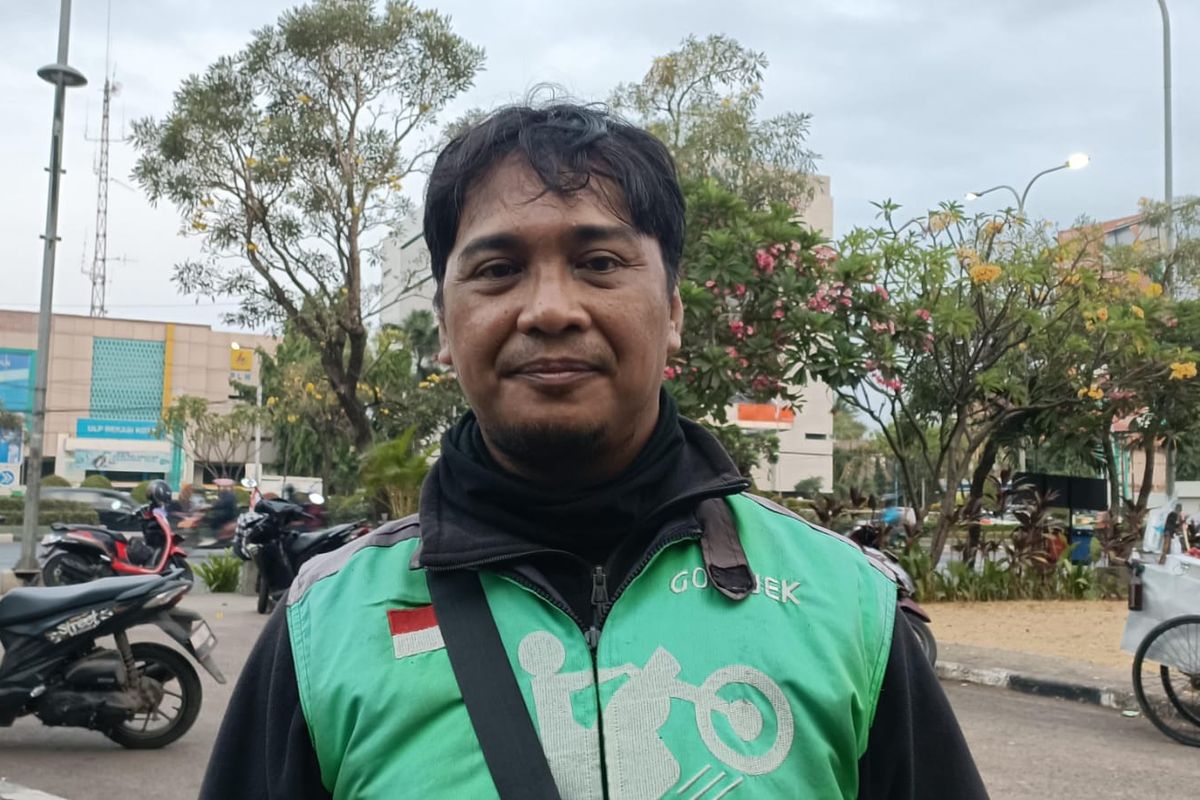 Adi (43) seorang pengemudi ojek online (ojol) saat ditemui Kompas.com, Selasa (10/10/2023). Pengemudi ojek daring yang merupakan warga Cawang, Jakarta Timur itu memberi rasa keberatan terkait wacana penerapan ganjil-genap bagi pengemudi sepeda motor.