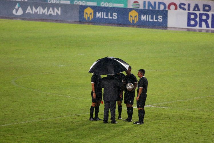 Wasit dan petugas pertandingan sedang berdiskusi dilapangan terkait lanjutan laga akibat hujan deras saat berlangsungnya pekan ke-17 Liga 1 2022-2023 antara PSS Sleman melawan Persija Jakarta di Stadion Manahan Solo, Jumat (23/12/2022) sore.