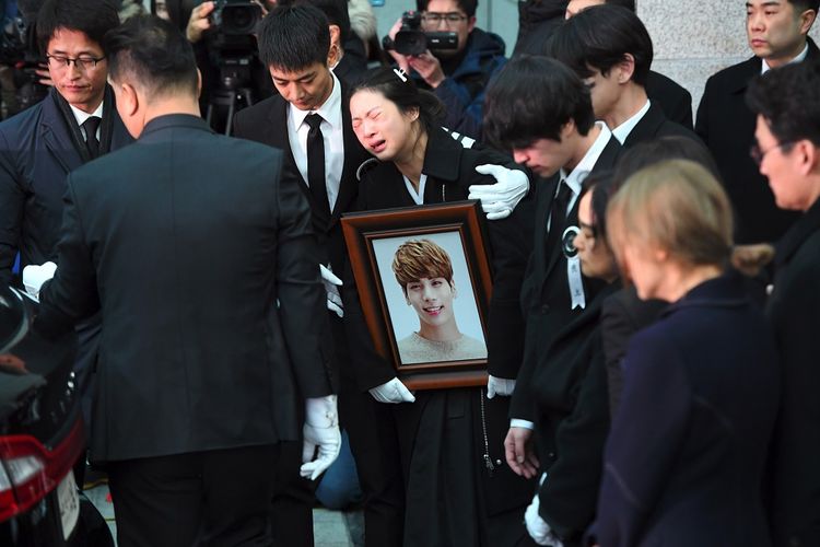 Kakak Jonghyun (memegang foto) menangis dalam pelukan Minho SHINee saat peti jenazah Jonghyun dimasukkan ke dalam mobil menuju tempat pemakaman dari rumah persemayaman di Asan Hospital, Seoul, Kamis (21/12/2017).