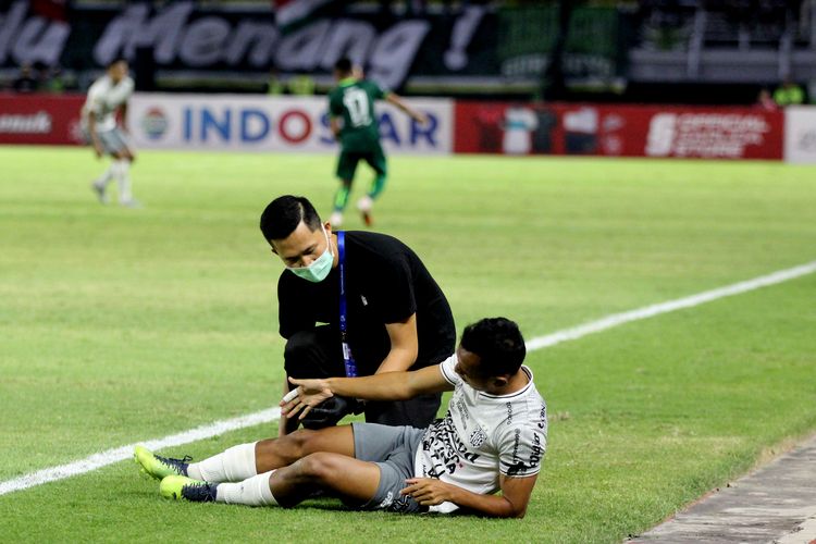 Dokter tim Bali United, Ganda Sedang memeriksa Irfan Jaya saat kesakitan berduel dengan pemain Persebaya Surabaya pada pertandingan pekan ke-8 Liga 1 2022-2023 yang berakhir 0-1 di Stadion Gelora Bun Tomo Surabaya, Jumat (2/9/2022) sore.