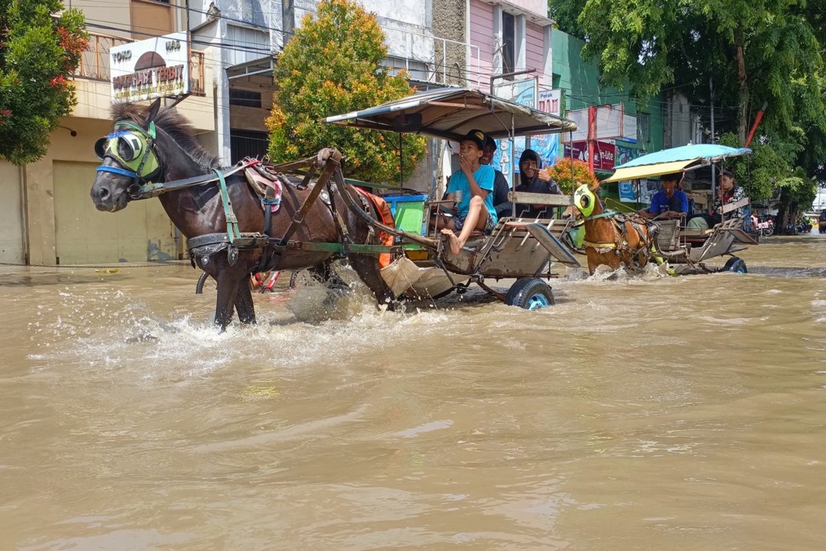 Kusir delman saat tengah mengantarkan penumpang melintasi banjir di Jalan Raya Dayeuhkolot, Kabupaten Bandung, Jawa Barat, Senin (31/11/2025) delman menjadi salah satu alternatif bagi warga dan pengendara yang tak berani menerjang banjir
