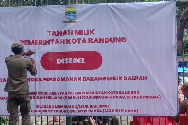 Petugas satpol PP memasang spanduk penyegelan di gerbang masuk Bandung Zoo, Kota Bandung, Kamis (5/2/2026)