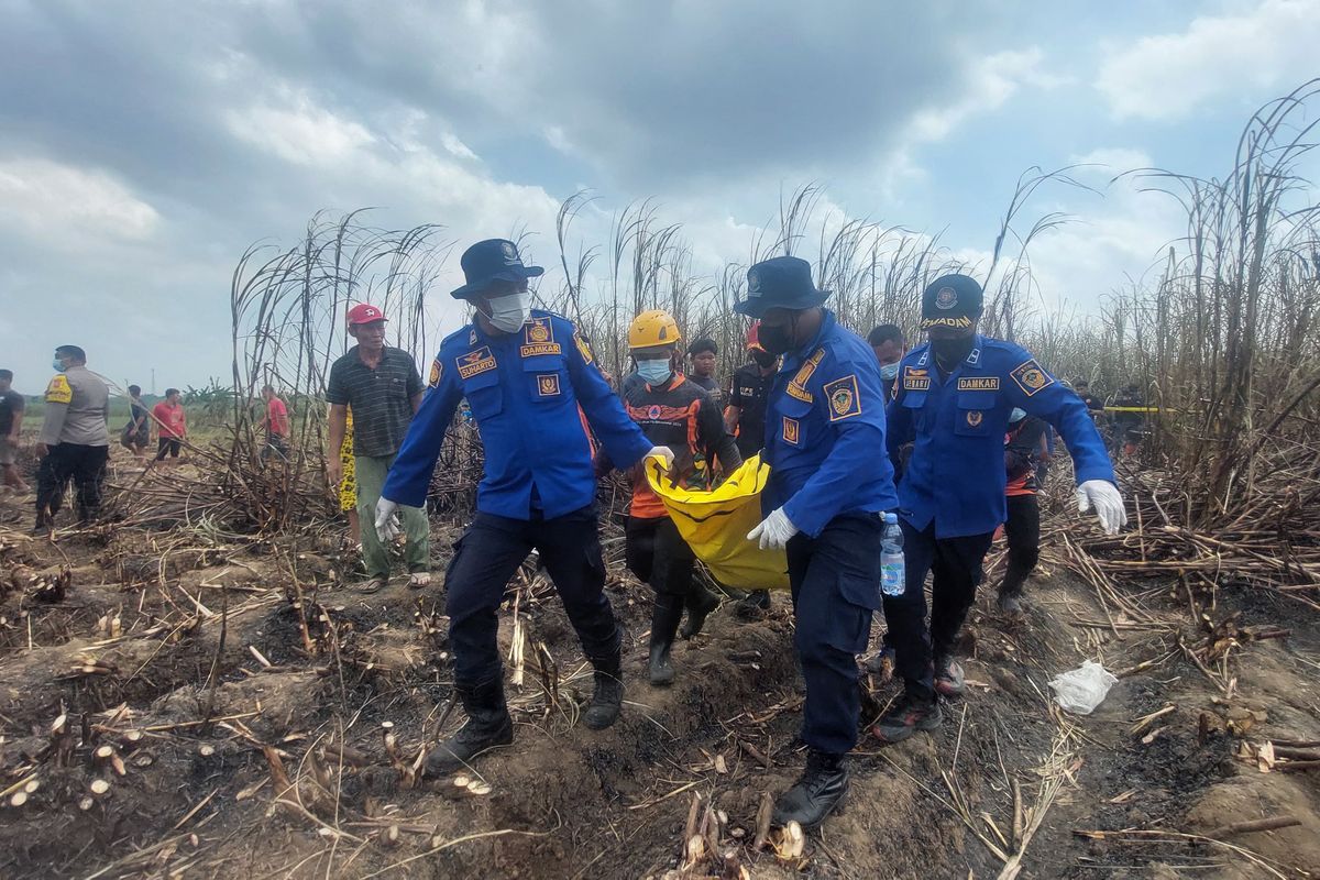 EVAKUASI-- Tim gabungan mengevakuasi jasad seorang petani ditemukan tewas diduga terjebak di lahan tebu yang terbakar, di Desa Candimulyo, Dolopo, Kabupaten Madiun, Senin (18/8/2025).