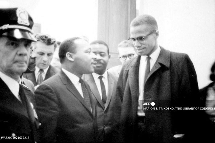 Foto selebaran Perpustakaan Kongres ini diterima pada 16 Februari 2005, menunjukkan Martin Luther King, Jr. (kiri) dan pemimpin Muslim kulit hitam Malcolm X (El-Hajj Malik El-Shabazz), 26 Maret 1964, menunggu konferensi pers di lokasi yang tidak diketahui. 21 Februari 2005 berikutnya menandai peringatan 40 tahun kematian Malcolm X yang dibunuh di Audubon Ballroom, di Harlem, New York pada tahun 1965.