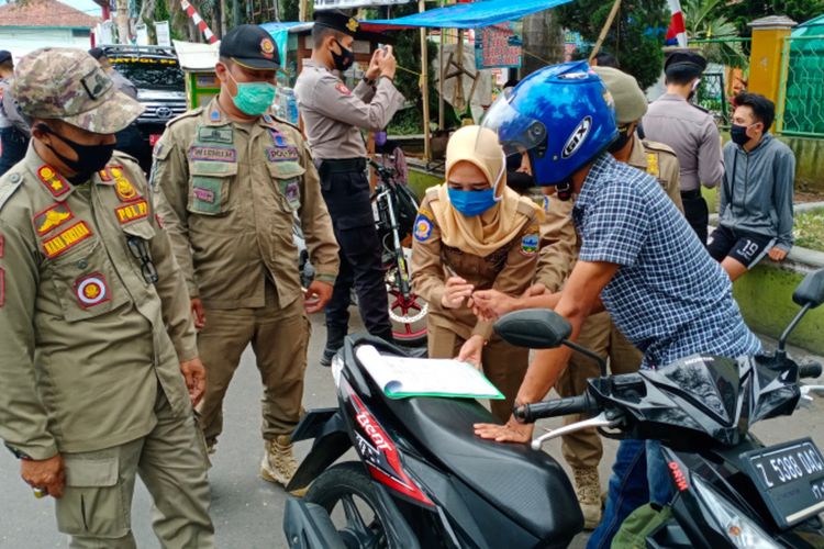 Anggota Satpol PP Kabupaten Garut mencatat identitas warga yang tidak menggunakan masker saat berkendara dal razia masker, Senin (24/08/2020)
