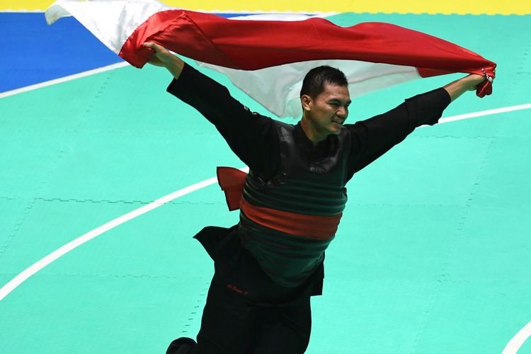 Pesilat Indonesia Aji Bangkit Pamungkas berlari membentangkan bendera merah putih usai mengalahkan pesilat Singapura Sheik Ferdous Sheik Alauddin dalam babak final Kelas I Putra Asian Games 2018 di Padepokan Pencak Silat Taman Mini Indonesia Indah (TMII), Jakarta, Senin (27/8/2018).