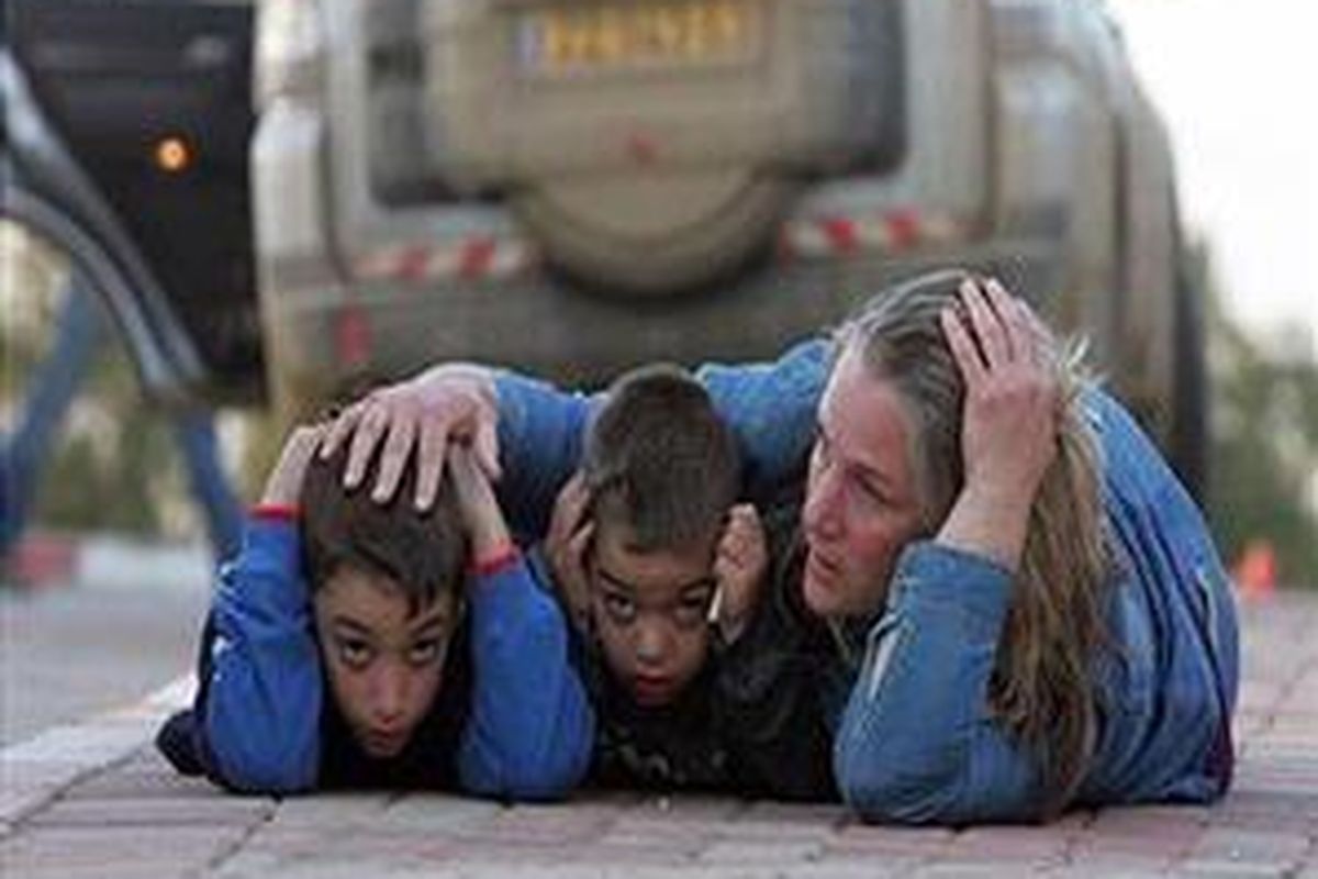 Seorang ibu warga Israel melindungi anaknya saat terjadi serangan roket oleh pejuang Palestina di  Kfar Aza, Israel selatan yang berbatasan dengan Gaza.