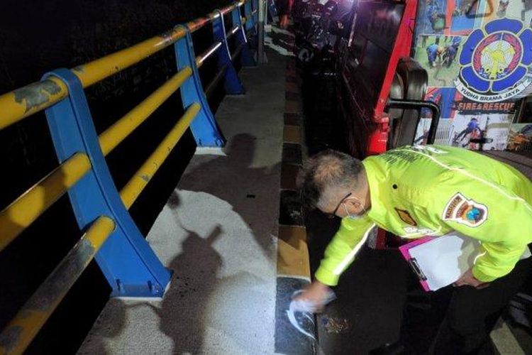Anggota Gakkum Satlantas Polresta Malang Kota saat memberikan tanda ke median jalan Jembatan Tunggulmas yang ditabrak oleh korban dan membuat korban terlempar terjatuh dari jembatan. (Tribun Jatim/Kukuh Kurniawan)
