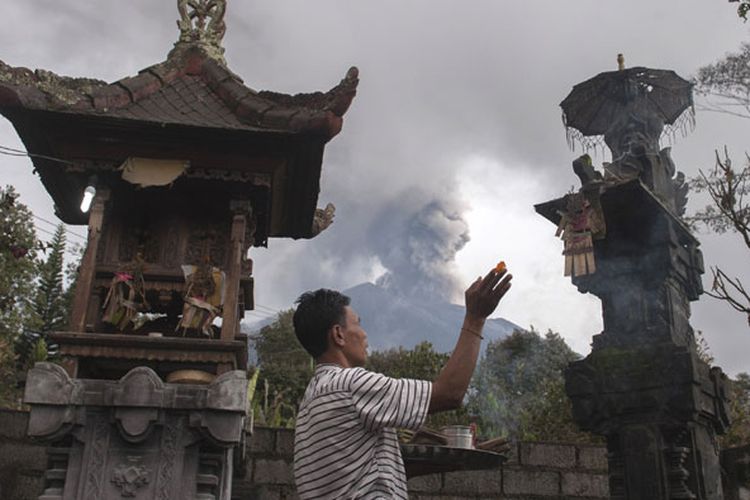 Warga berdoa di rumahnya di Desa Besakih, Karangasem, Bali, Selasa (28/11/2017). Pusat Vulkanologi dan Mitigasi Bencana Geologi memantau kolom abu gunung bertambah tinggi hingga 4.000 meter dalam enam jam terakhir sejak pukul 06.00 Wita pada Selasa (28/11/2017).