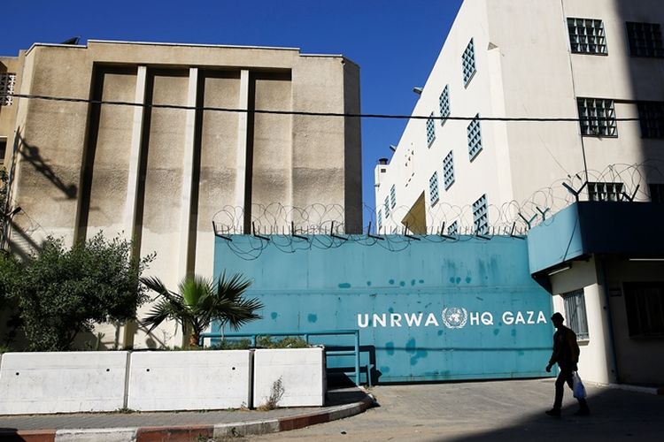 Warga Palestina melintas di depan markas besar UNRWA di Gaza.