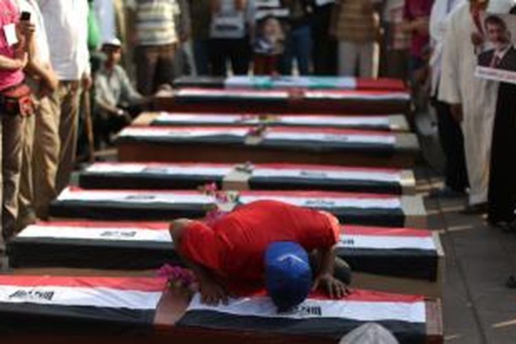 Seorang pendukung Muhammad Mursi, mencium sebuah peti mati kosong yang melambangkan para pendukung Ikhwanul Muslimin yang tewas setelah ditembaki tentara Mesir pada Selasa (9/7/2013).