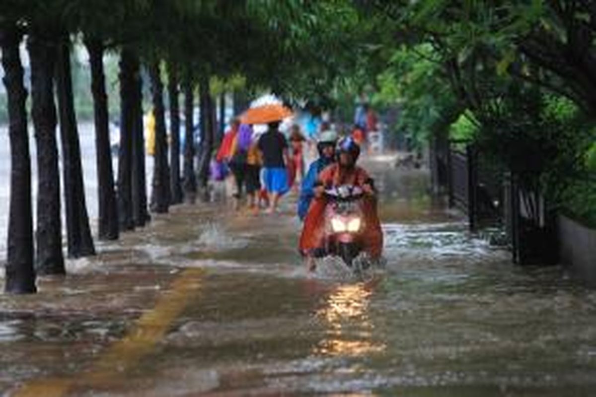 Warga melintas di Jalan MH Thamrin saat hujan mengguyur Jakarta, Senin (9/2/2015). Hujan lebat mengakibatkan sejumlah ruas jalan di Jakarta dan sekitarnya terendam banjir dan menyebabkan kemacetan.