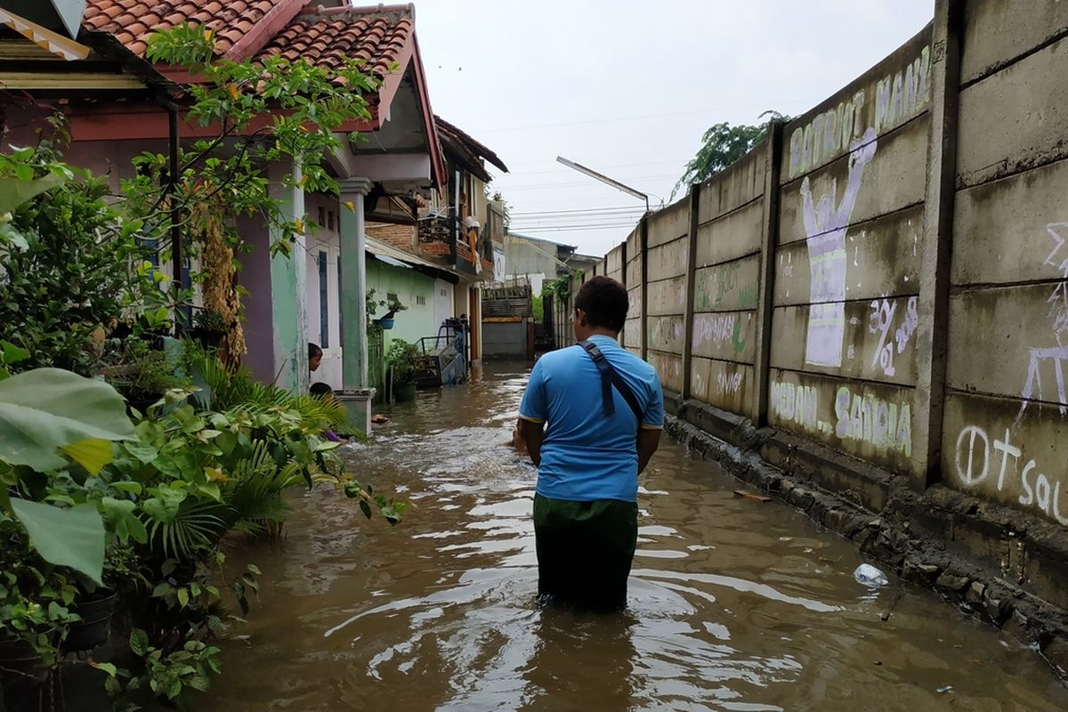 Seorang warga Kampung Buaran Jaya, Harapan Mulya, Medansatria, Kota Bekasi menembus banjir yang merendam perumahannya pada Selasa (21/1/2020) pagi.