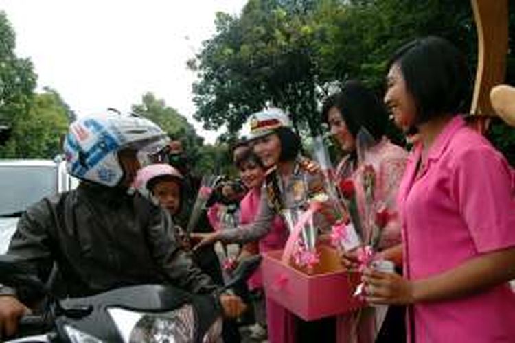 Sejumlah polisi wanita (Polwan) Polres Bogor Kota mengenakan busana kebaya memberikan bunga mawar dan cokelat kepada para pengguna jalan yang melintas di depan Tugu Kujang, Kota Bogor, dalam rangka memperingati hari Kartini, Rabu (20/4/2016). 