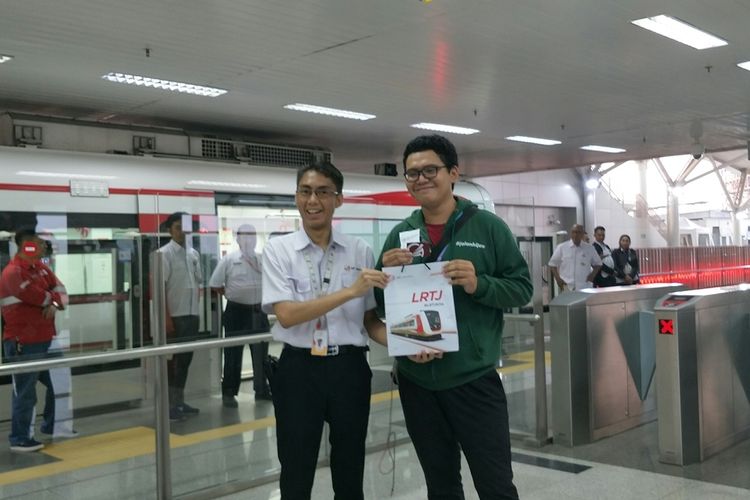 Penumpang mendapatkan cendera mata dari PT LRT Jakarta pada hari pertama pengoperasian moda transportasi LRT Jakarta secara komersil, Minggu (1/12/2019).
