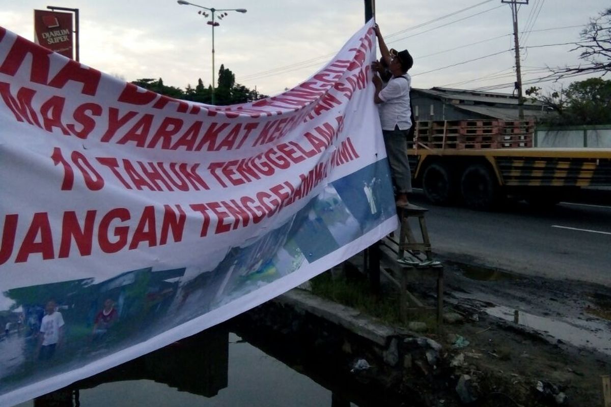 Spanduk bernada protes terpasang  di jalur Pantura Sayung,  Demak,  agar segera dibangun tanggul laut untuk antisipasi banjir rob,  Minggu (5/12/2017)