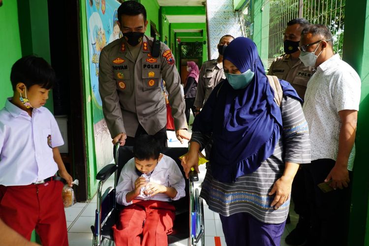 Kapolres Semarang AKBP Yovan Fatika mendorong kursi roda siswa SLB yang akan mengikuti vaksinasi
