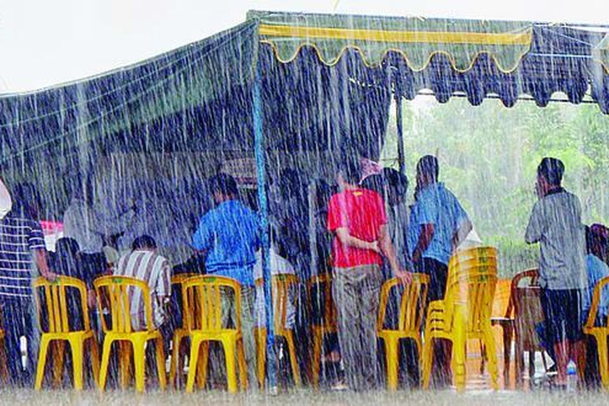 Di bawah guyuran hujan deras, warga Kota Samarinda mengikuti penghitungan suara di TPS 22 Kelurahan Air Putih, Kota Samarinda, Kalimantan Timur, Senin (26/5). Sebanyak 2,255 juta pemilih menentukan satu dari empat pasangan calon sebagai gubernur dan wakil gubernur baru Kaltim.