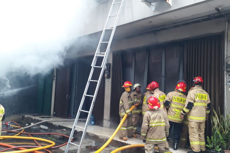 Petugas pemadam kebakaran berupaya memadamkan api yang melalap rumah toko (ruko) di Jalan Ruko Permata, Pademangan, Jakarta Utara pada Senin (26/12/2022).  