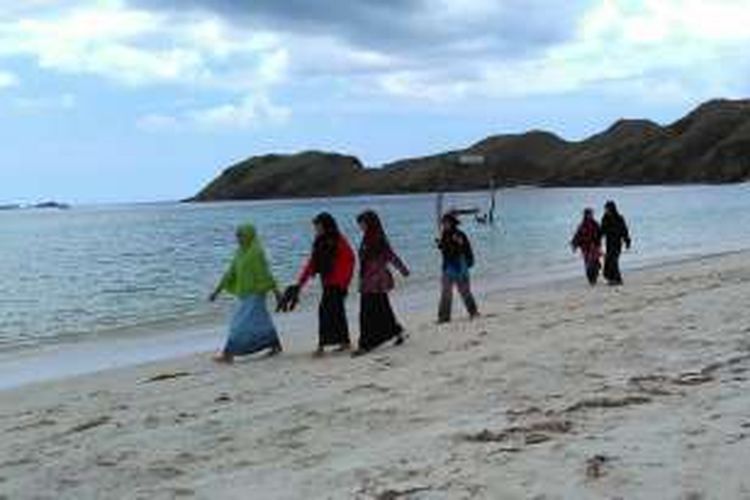 Beberapa wisatawan berjalan di Pantai Tanjung Aan, Lombok Tengah, Nusa Tenggara Barat.