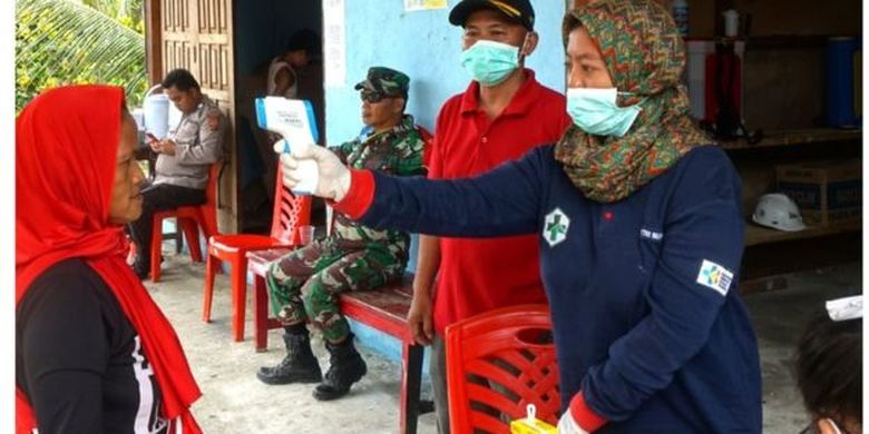 Petugas kesehatan memeriksa suhu tubuh salah satu warga di Arsopura, Distrik Skanto, Kabupaten Keerom, Papua, (13/04). 