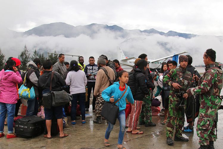 Warga menunggu pesawat dengan penjagaan aparat keamanan di Bandara Ilaga, Kabupaten Puncak, Papua, Rabu (2/10/2019). Masyarakat Ilaga, Kabupaten Puncak mulai mengungsi pascateror penembakan dan pembakaran oleh kelompok sipil bersenjata.