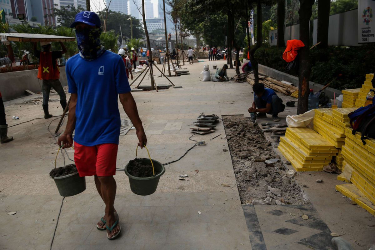 Pekerja menyelesaikan revitalisasi trotoar dan taman di kawasan jalan Sudirman, Jakarta Pusat, Kamis (19/7/2018). Penataan trotoar dan taman ditargetkan selesai pada akhir bulan Juli sebelum pelaksanaan Asian Games 2018.