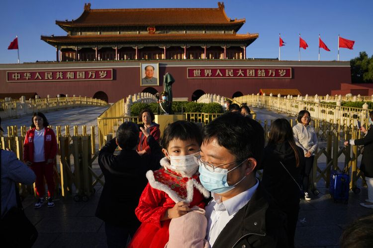 Seorang pria dan seorang anak memakai masker saat mereka mengunjungi Gerbang Tiananmen di Beijing, China, Jumat, 15 Oktober 2021.
