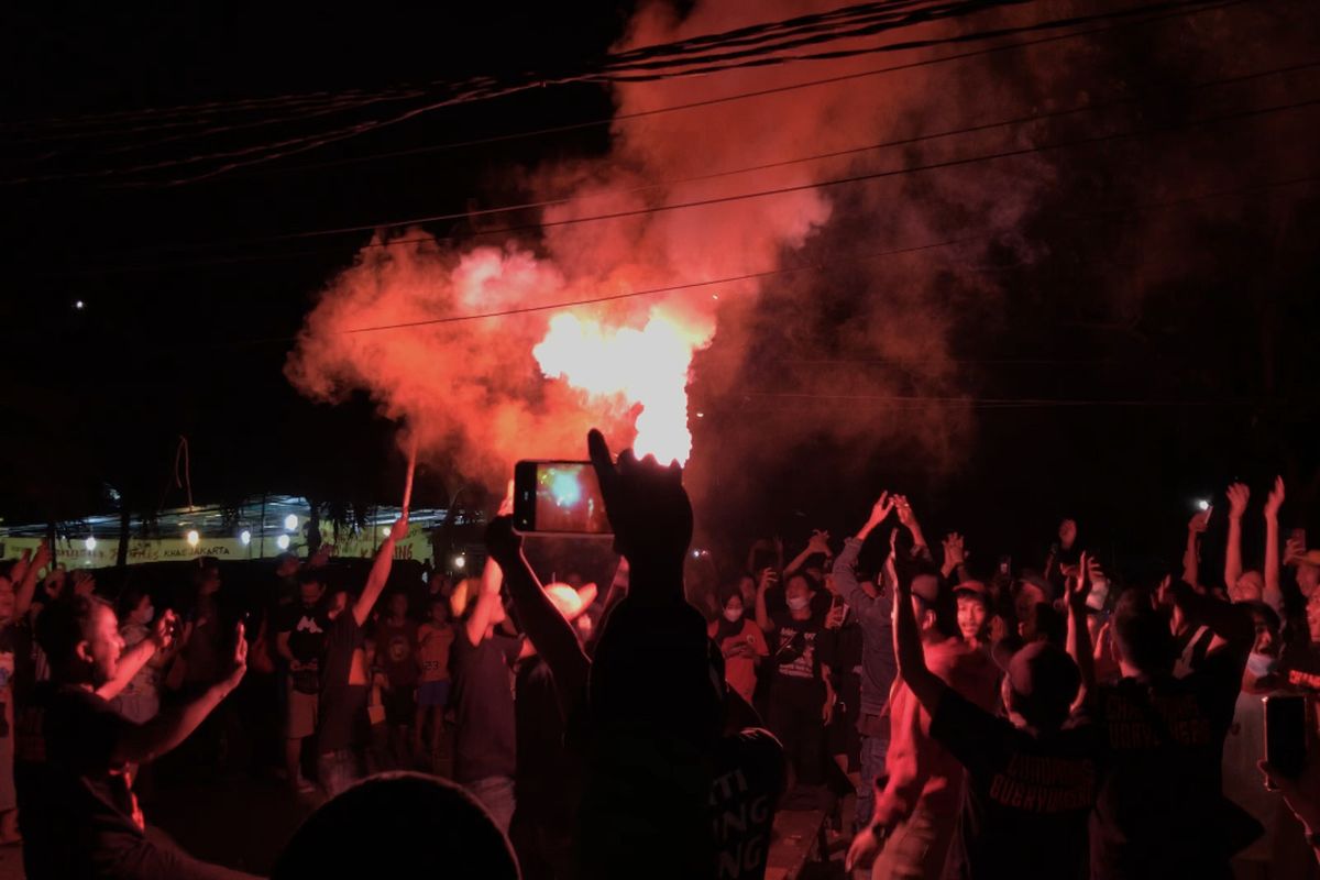 Sejumlah pendukung Persija merayakan kemenangan Persija Jakarta dengan bernyanyi sambil menyalakan flare seusai nonton bareng di pinggir Jalan Raya Pasar Minggu, Kalibata, Jakarta Selatan pada Minggu (25/4/2021) malam.