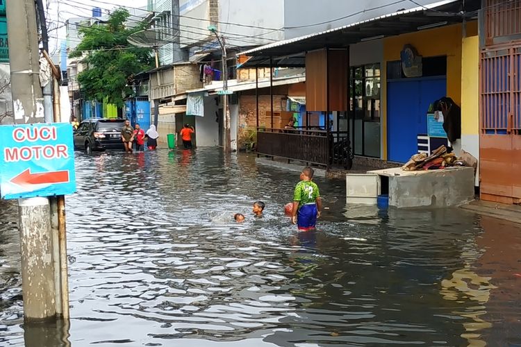 Bocah-bocah tampak girang bermain air banjir yang penuh sampah di kawasan Jalan Teluk Gong, Penjaringan, Jakarta Utara, Sabtu (4/1/2020).