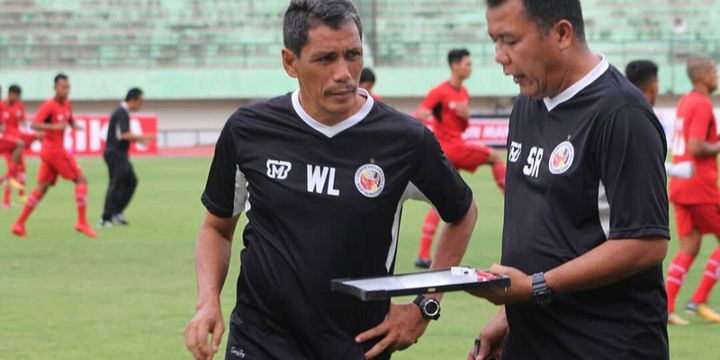 Pelatih kepala Semen Padang Syafrianto Rusli sedang berdiskusi dengan asistenya Weliansyah