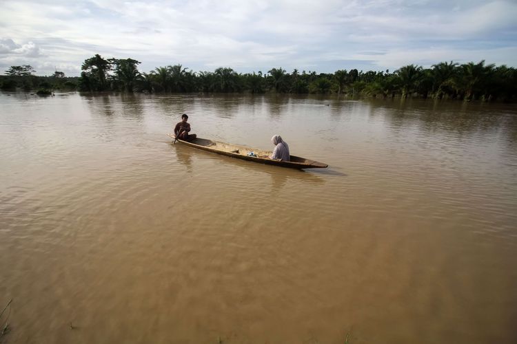 Warga menggunakan perahu melintas di tengah banjir yang merendam Desa Buket Linteueng, Kecamatan Langkahan, Aceh Utara, Aceh, Senin (23/1/2023). Menurut Badan Penanggulangan Bencana Daerah (BPBD) Aceh Utara, hujan deras yang mengguyur Aceh Utara dalam dua hari terakhir mengakibatkan tujuh kecamatan di Aceh Utara terendam banjir dan sebanyak 11.202 jiwa warga terdampak banjir serta 420 jiwa mengungsi.