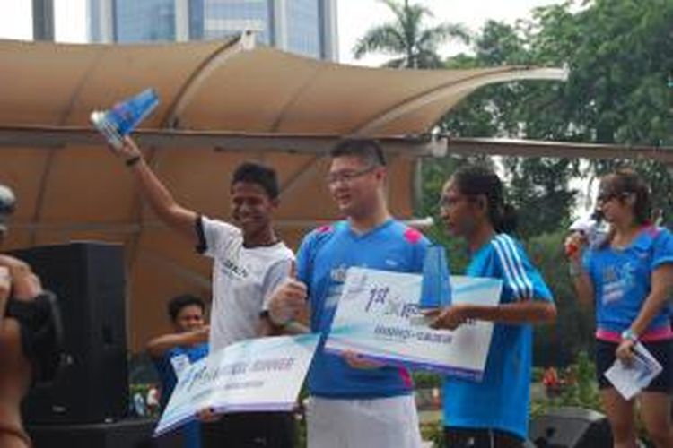 Juara vertical running kategori putra, Muhammad Taufik (kiri) dan juara kategori putri, Mutia Proborini (kanan) memamerkan piala di Menara BCA, Sudirman, Jakarta, Minggu (13/10/2013).
