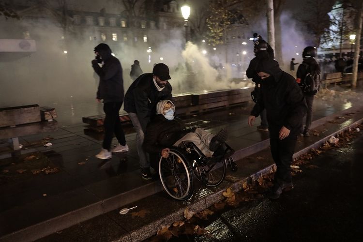 Demonstran meninggalkan arena kerusuhan di sekitar Place de la Republique setelah aksi demonstrasi pada Sabtu (5/12/2020) di Paris, Perancis. Ribuan orang turun ke jalan  menentang rancangan undang-undang keamanan. Kerusuhan dengan cepat meningkat Paris ketika penyusup membakar beberapa mobil, memecahkan jendela, dan melemparkan proyektil ke arah polisi.