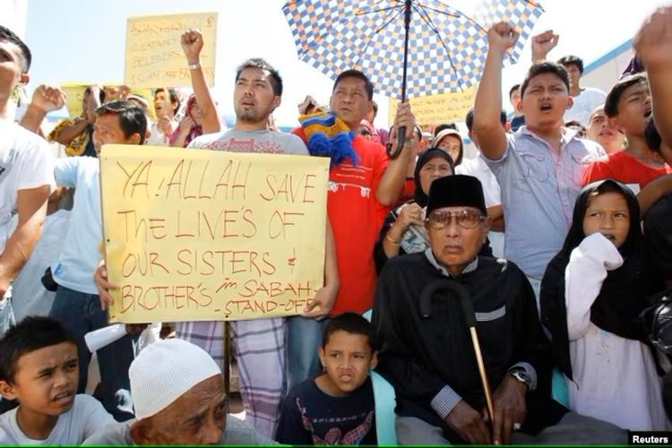 Mantan Sultan Sulu Jamalul Kiram III (duduk di kanan) bersama para pengikutnya memasang plakat di depan Masjid Biru di desa Maharlika, Kota Taguig, selatan Manila, 1 Maret 2013.