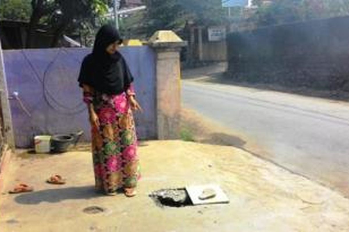 Maryani menunjukkan lokasi jatuhnya tabung gas di depan rumahnya.