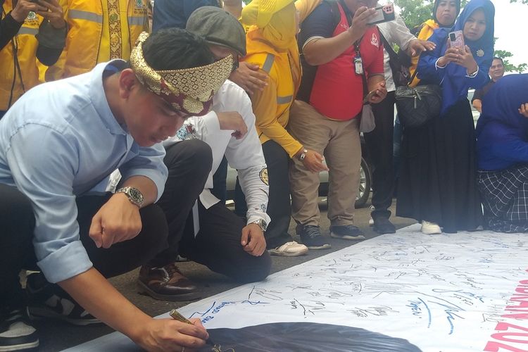Bacawapres Gibran Rakabuming Raka menandatangani baliho dukungan relawannya usai membeili motor Vesapa, di Palembang, Minggu (12/11/2023)