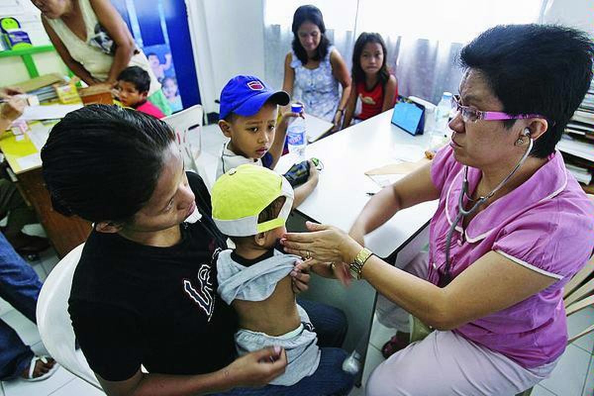 Dokter Filipina memeriksa kesehatan seorang anak balita di pusat kesehatan di Taguig, Manila. Filipina menerapkan asuransi wajib bagi warga negaranya dengan jaminan tarif rawat inap yang sama di seluruh Filipina.