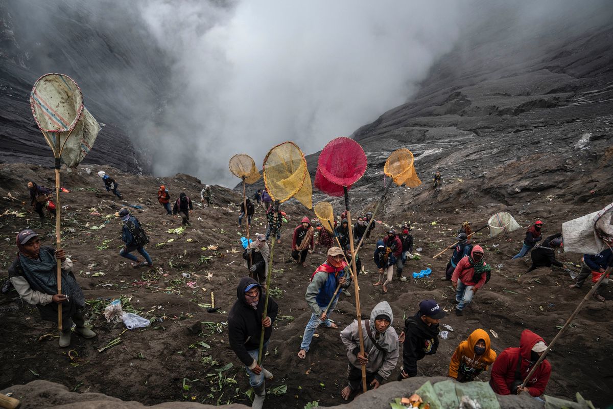 Villagers use nets to catch offerings thrown by members of the Tengger sub-ethnic group in the crater of the active Mount Bromo volcano as part of the Yadnya Kasada festival in Probolinggo, East Java province on June 16, 2022. Juni Kriswanto / AFP