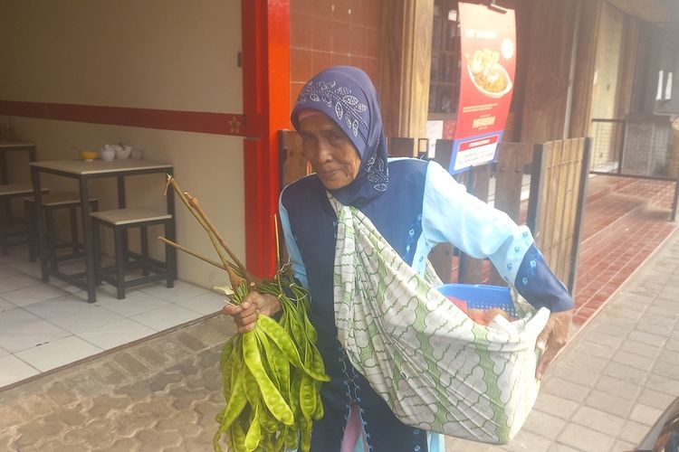 Di usia senjanya, Komariah (74) tetap semangat mencari nafkah dengan berjalan kaki menyusuri trotoar jalan di wilayah Sumedang kota, berjualan hasil kebun, Jumat (22/12/2023). AAM AMINULLAH/KOMPAS.com