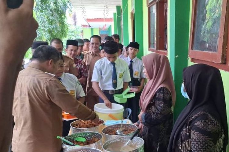 Pj Bupati Aceh Besar Muhammad Iswanto menaruh lauk pauk kepada siswa SMPN I Darul Imarah di sela-sela meluncurkan simulasi makan siang gratis bergizi di Darul Imarah, Selasa (5/3/2024).