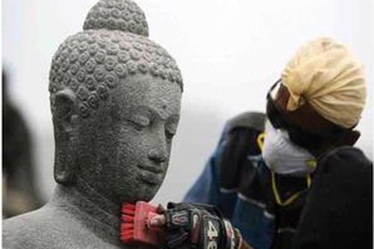 Petugas membersihkan arca Buddha dari abu vulkanik Gunung Merapi di Candi Borobudur, Borobudur, Kabupaten Magelang, Jawa Tengah, Sabtu (13/11). Rencananya sebanyak 72 stupa dan sejumlah arca yang telah bersih secara bertahap akan ditutup dengan plastik agar tidak lapuk terkena abu.