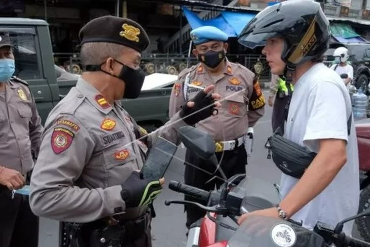 Polisi menegur warga negara asing (WNA) yang tidak mengenakan masker saat razia masker di Denpasar, Bali, Sabtu (5/2/2022).